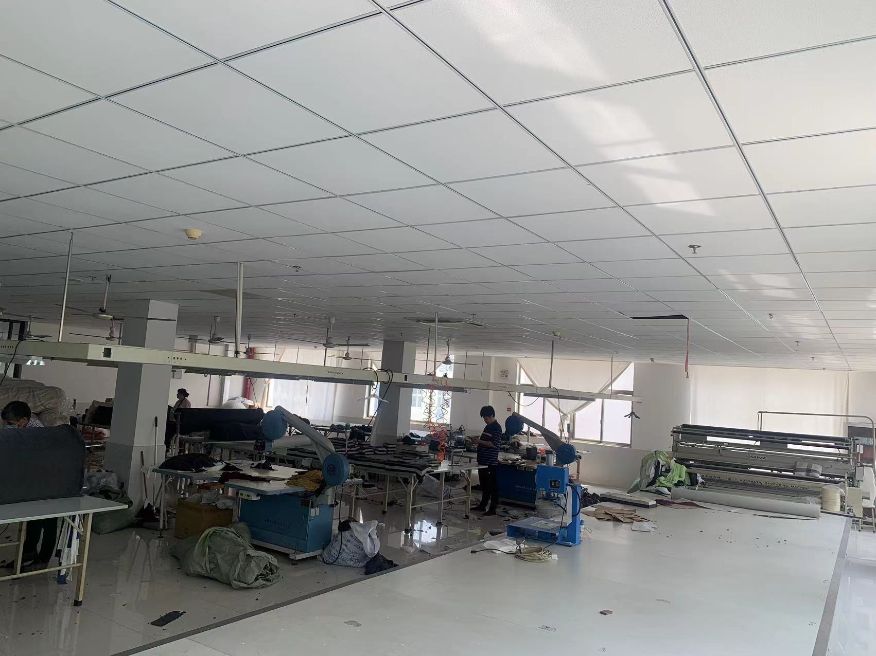 Cutting workshop in garment factory with professional cutting equipment, fabrics & tools, suitable for fabric cutting production.