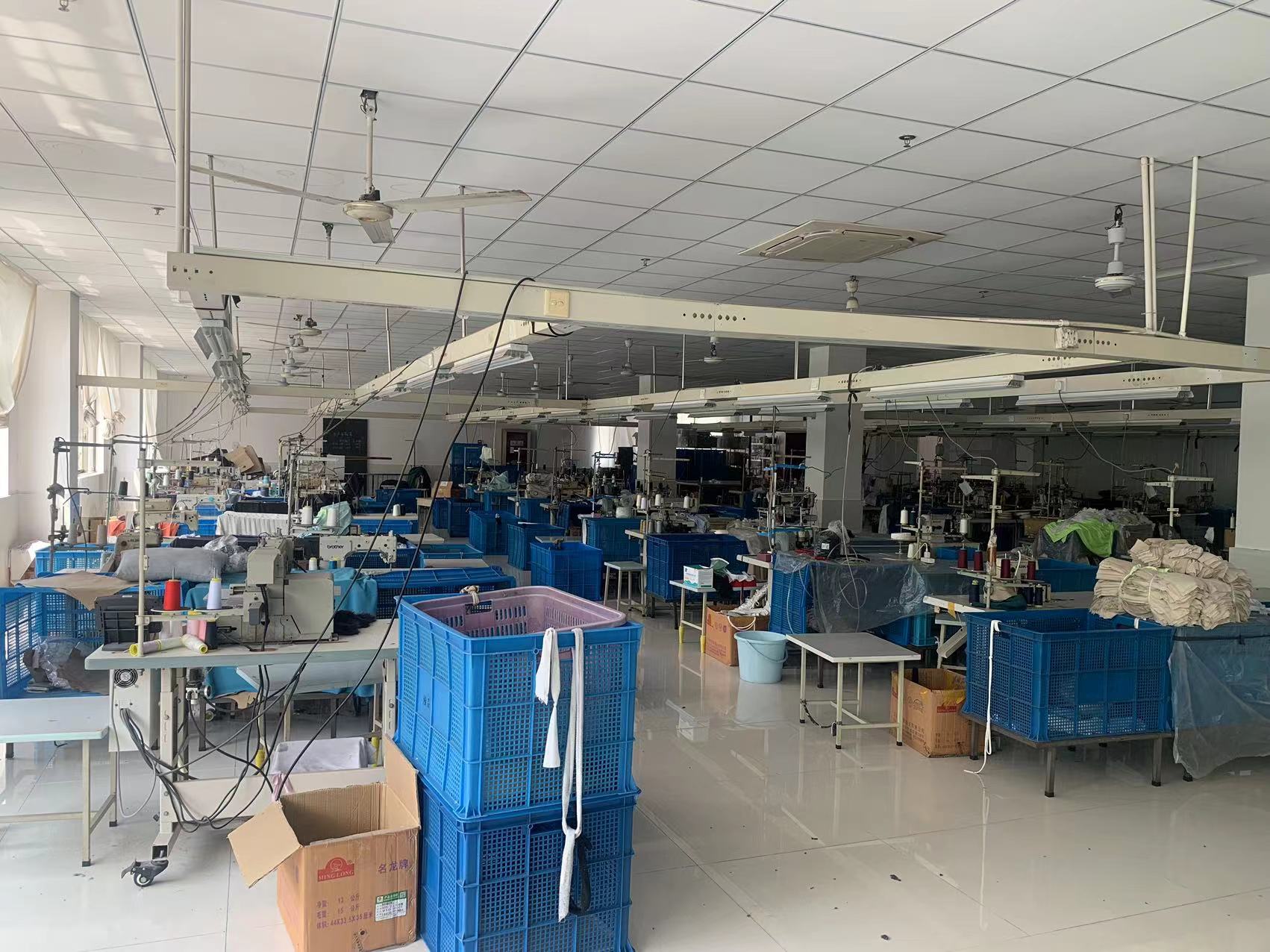 Sewing workshop in garment factory with sewing machines & blue turnover baskets, orderly for garment sewing production.
