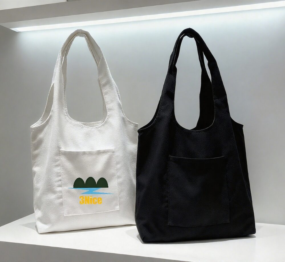 White canvas tote bag with "3Nice" text and landscape graphic, plus black canvas tote bag (still life)