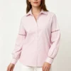 Light pink collared shirt-front Woman wearing a light pink collared shirt with lace - cutout details on sleeves and white pants