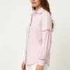 Light pink collared shirt-side Woman wearing a light pink collared shirt with lace - cutout details on sleeves and white pants