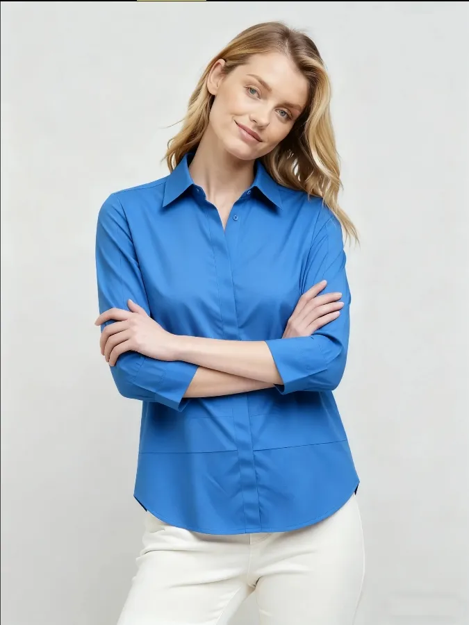 Woman wearing a bright blue collared shirt with 3/4 sleeves and white pants
