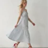 Model walking, showing the movement of the tiered midi skirt on a light grey blue cami dress