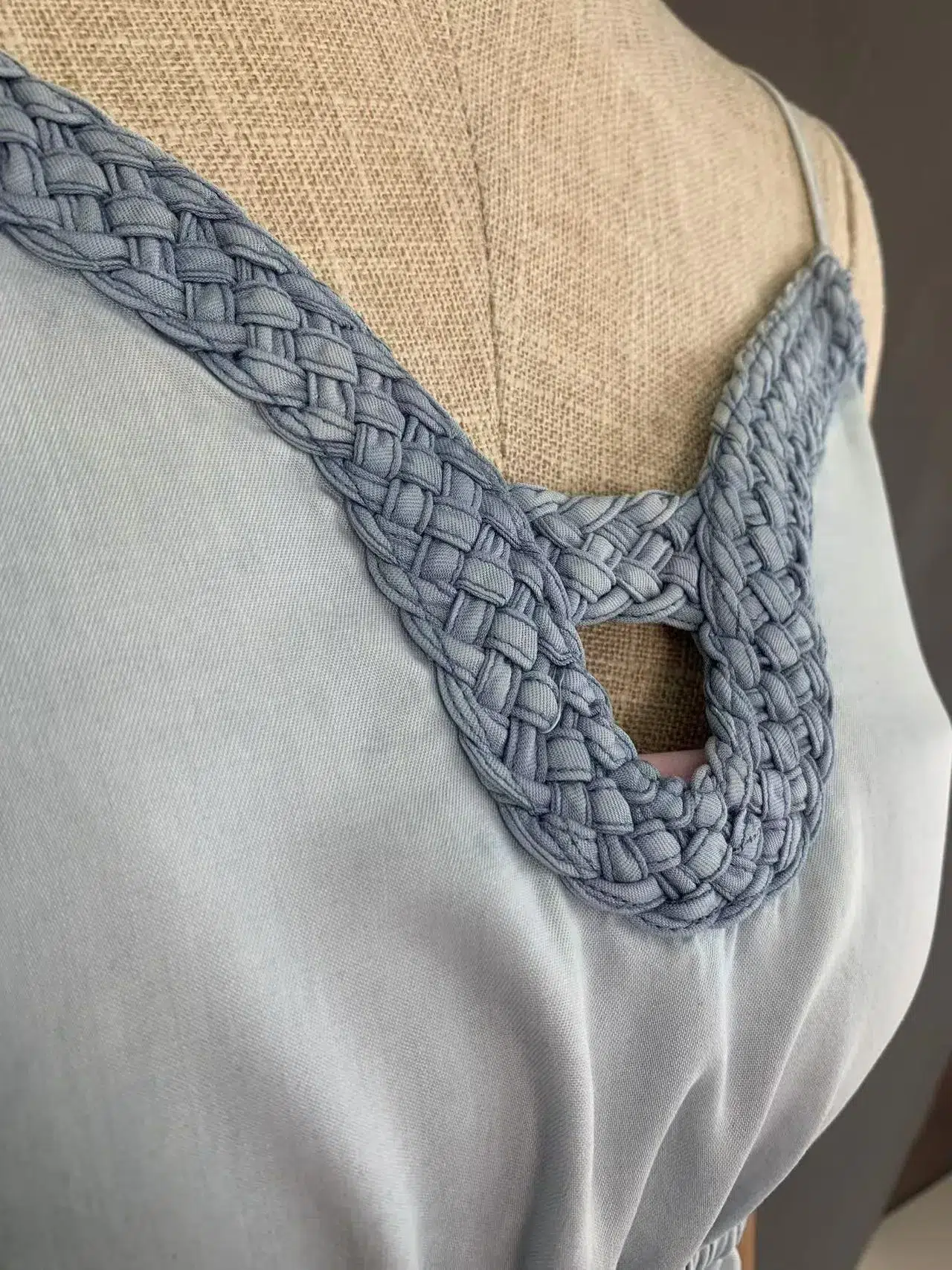 Close-up of the handcrafted crochet trim on the V-neckline of a light grey blue cami midi dress