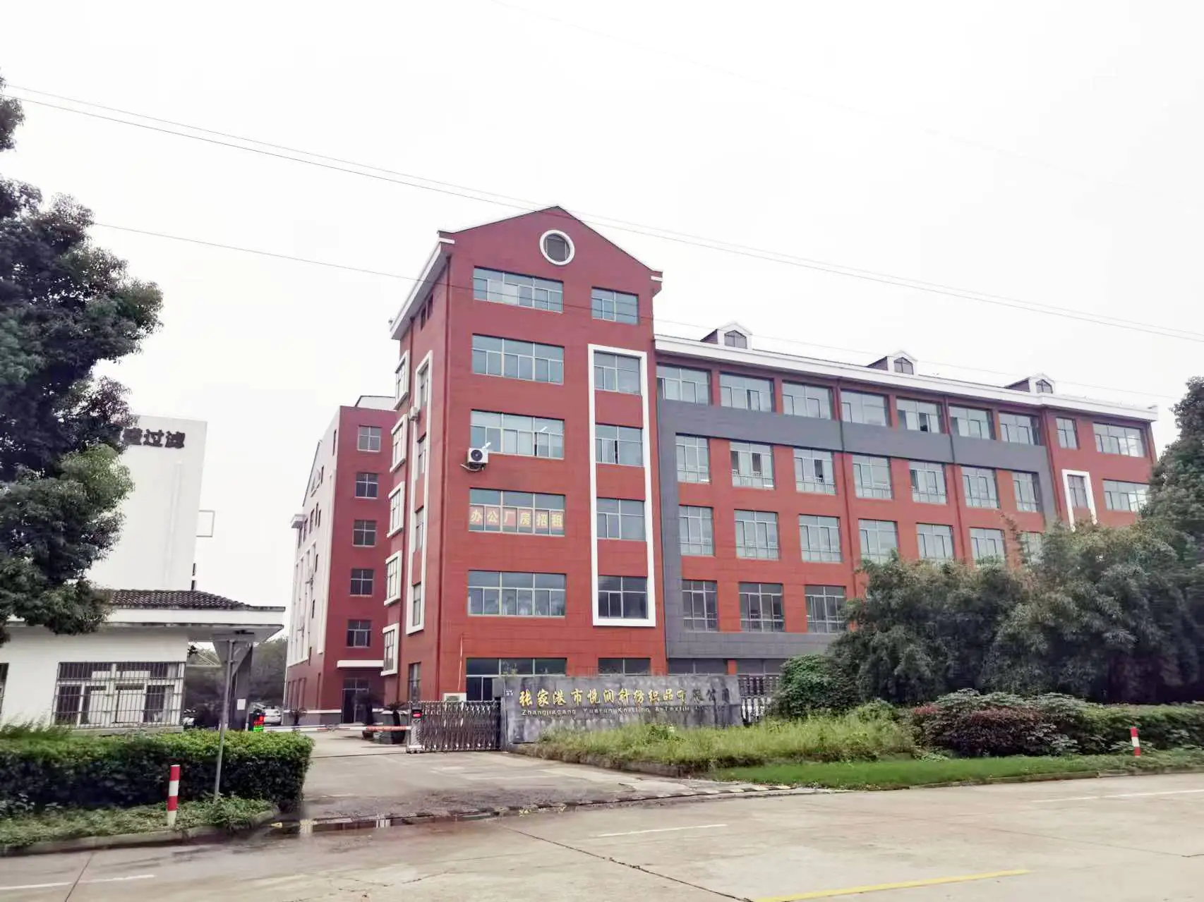 Main gate of garment factory with red-brick industrial building & entrance area, suitable for factory entry & image display.
