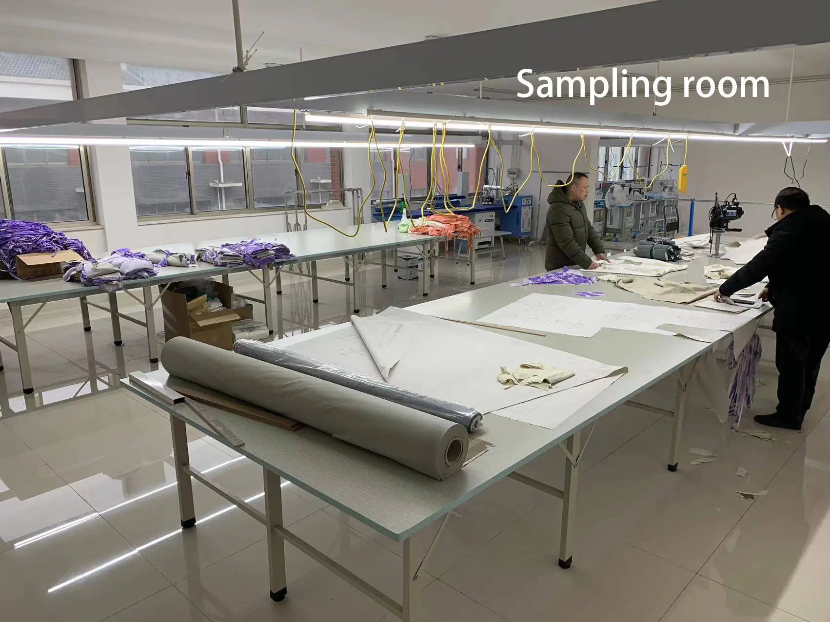 Sample cutting and ironing workshop with cutting tables, fabric rolls & ironing tools, suitable for sample cutting and ironing operations.