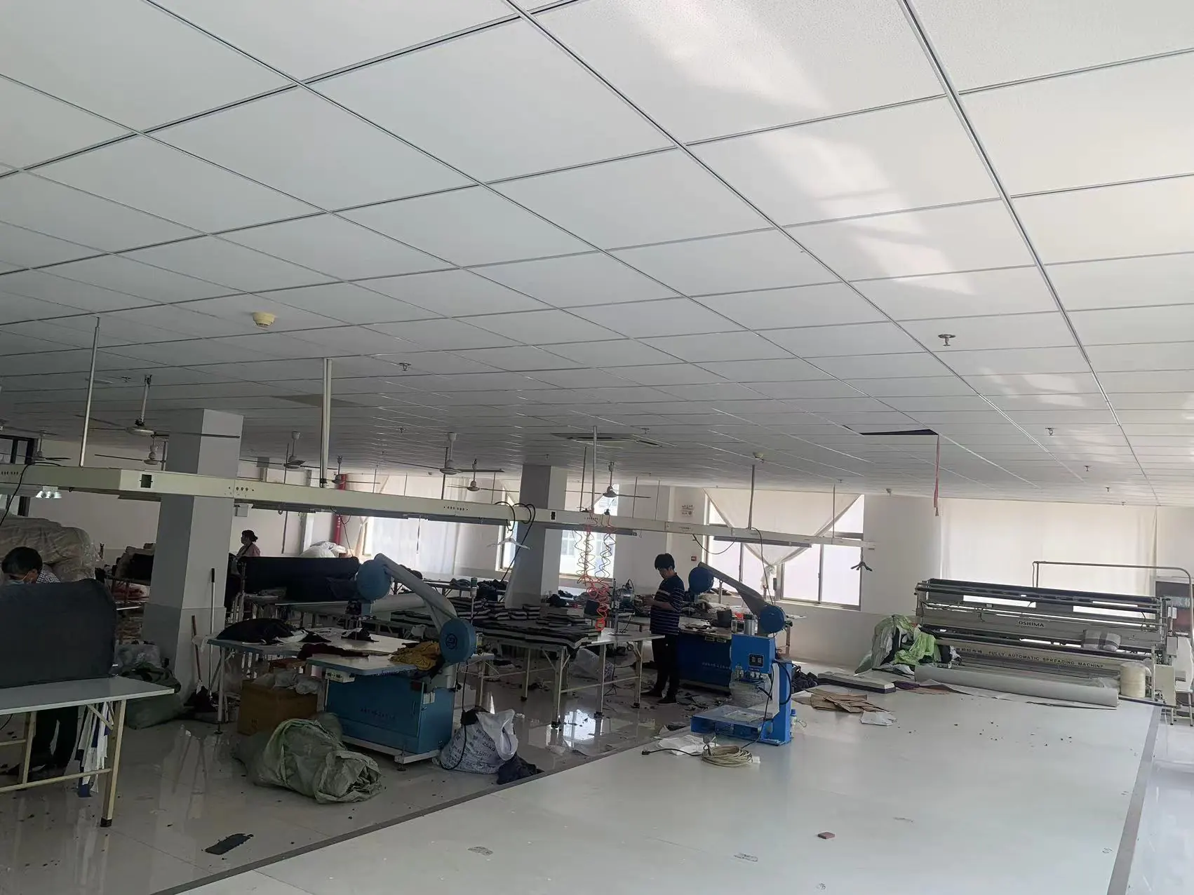 Cutting workshop in garment factory with professional cutting equipment, fabrics & tools, suitable for fabric cutting production.