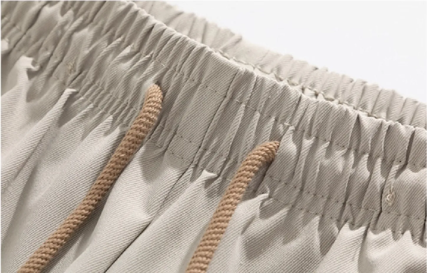 Detail view of light beige drawstring wide-leg trousers’ waist (drawstring and elastic detailing)