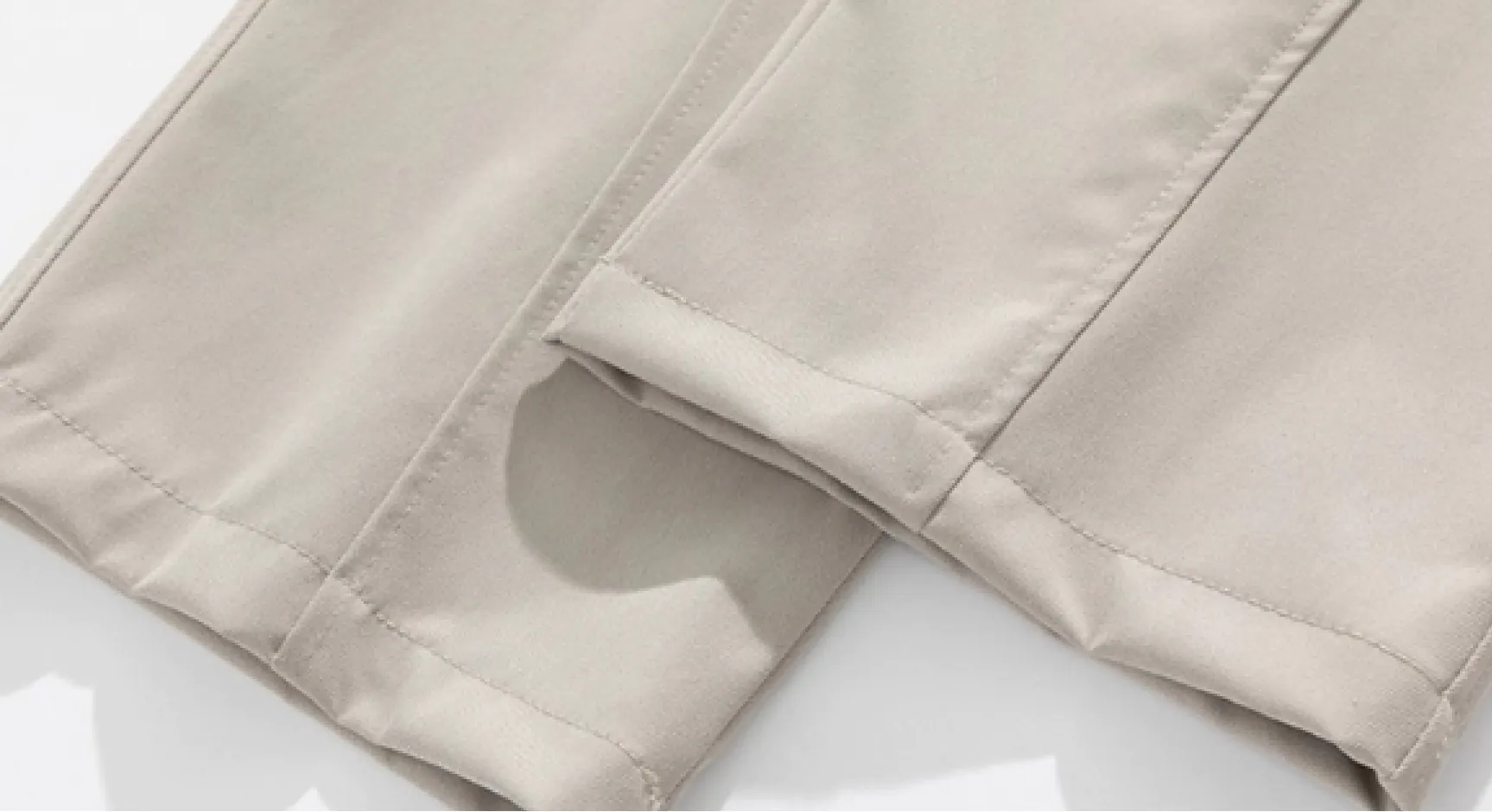 Detail view of light beige drawstring wide-leg trousers (hem stitching and fabric texture)