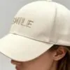 beige-smile-embroidered-baseball-cap-model.jpg Model wearing beige baseball cap with "SMILE" embroidery