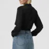 black-collared-long-sleeve-top-with-blue-denim-bottoms.jpeg Black collared long - sleeve top paired with blue denim bottoms, featuring a minimalist and sleek design, suitable for daily or light workplace wear.