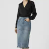 black-v-neck-top-with-blue-denim-skirt.jpeg Black V - neck long - sleeve top paired with blue frayed denim midi skirt, featuring a minimalist and sleek design, suitable for daily or light workplace wear.