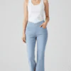 Outfit with light blue crossover waist flared jeans and white tank top, featuring a casual, fashionable, and retro - styled design.