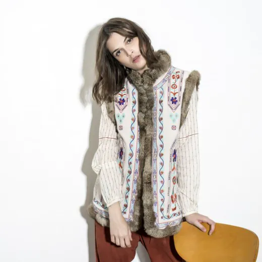 embroidered-vest-with-rabbit-fur-trim-full-view-model-display.jpg Model wearing embroidered vest with rabbit fur trim, paired with patterned top and reddish-brown pants